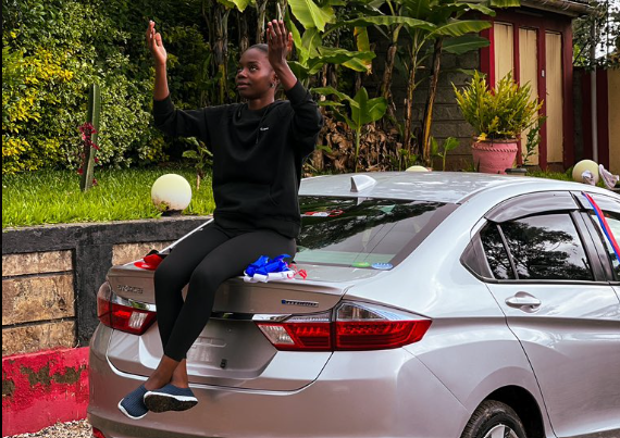Sueh Owino on top of the car her husband bought her.